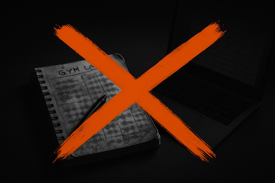 A gym notebook and a laptop spreadsheet crossed out with a bold orange X